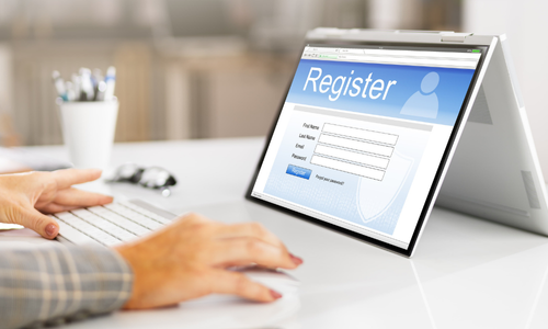 Osoba używa laptopa w trybie tabletu z wyświetloną stroną rejestracji użytkownika.